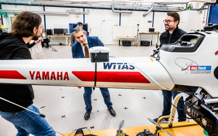 Piotr Rudol och Mariusz Wzorek står i ett robotlabb med ministern och demonstrerar den ombyggda helikoptern.