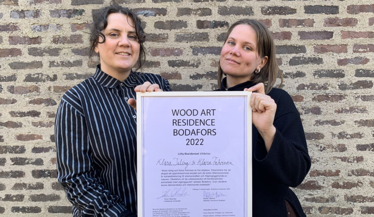 Klara Isling och Klara Fahrman håller upp en tavla med utmärkelsen.