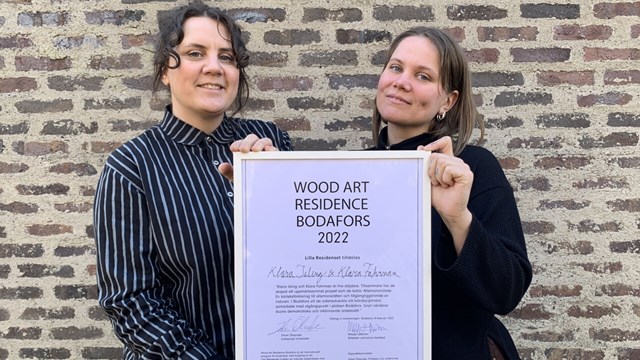 Klara Isling och Klara Fahrman håller upp en tavla med utmärkelsen.