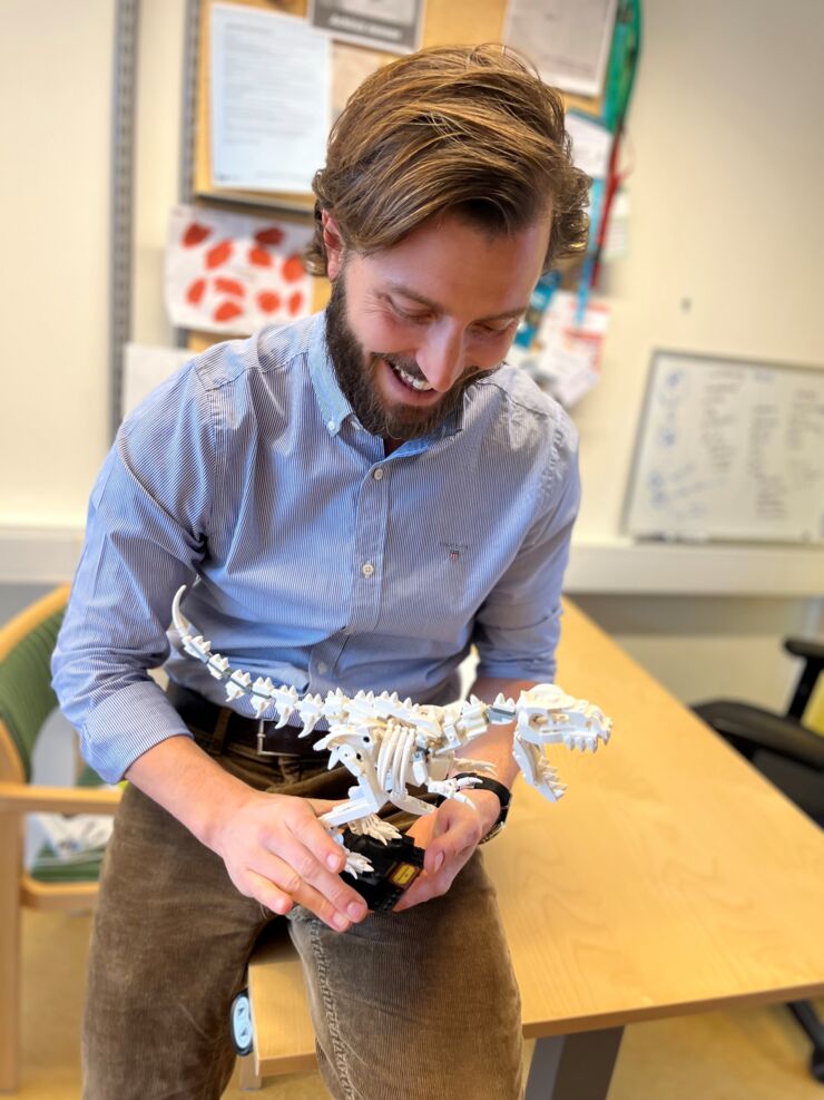 Claudio Cantù holds a design of Tyrannosaurus Rex made from LEGO that sits on his bookshelf in his office.
