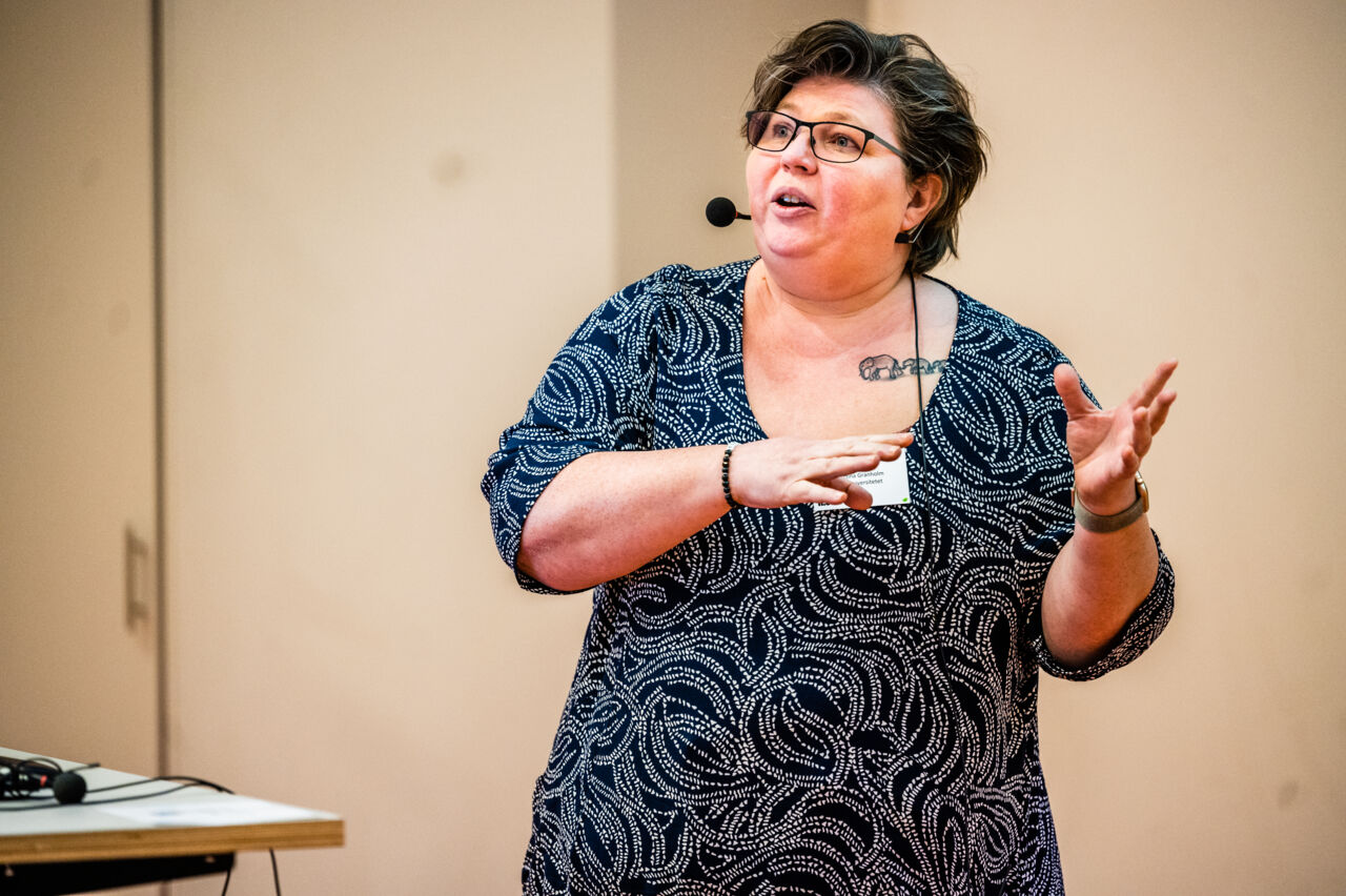 Kvinna med mikrofon håller tal.