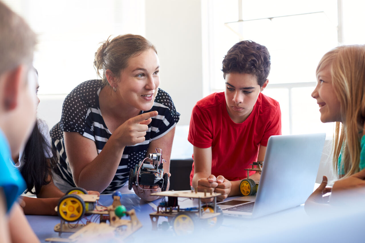 Happy teacher with students building a robot.