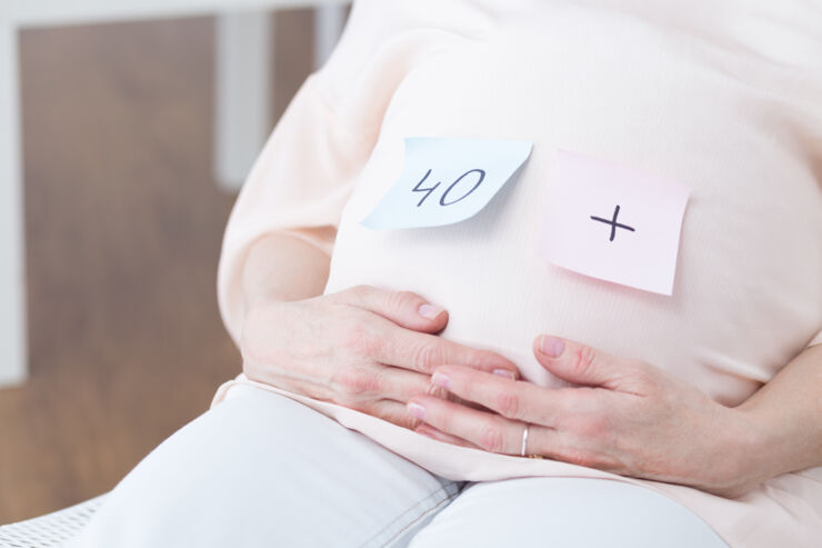 Close-up of woman after forties touching her pregnant belly.