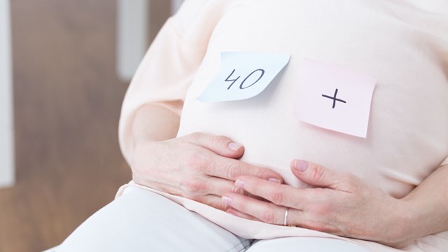 Close-up of woman after forties touching her pregnant belly.