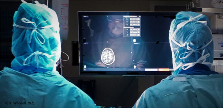 Två sjukvårdspersonal står framför en skärm där en genomlyst hjärna syns.