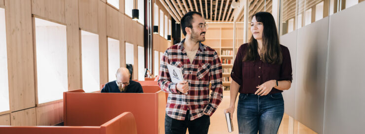 Two students walking and talking in a corridor on campus