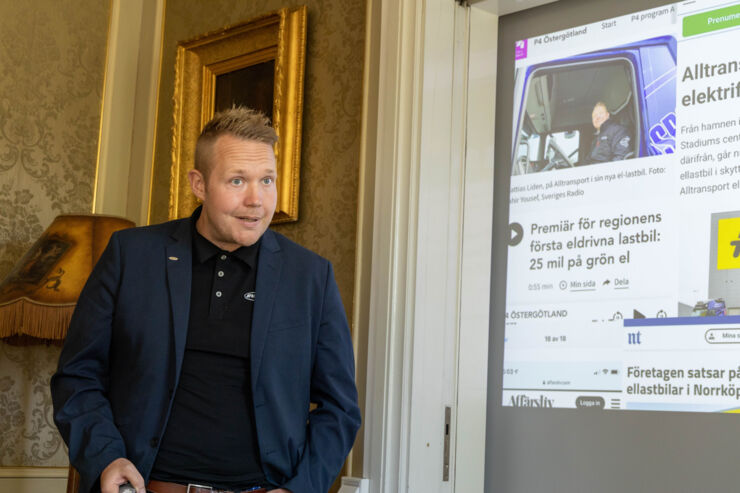 En man står framför en duk där en presentation projiceras