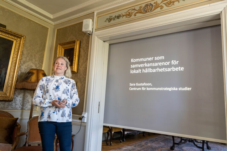 En kvinna står framför en presentation som projiceras på en duk