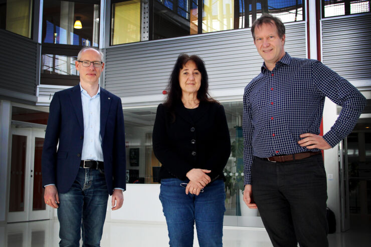 The three people who have been interviewed stand next to each other in a bright room.