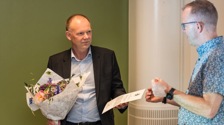 Två män varav ena håller blomkvast och diplom