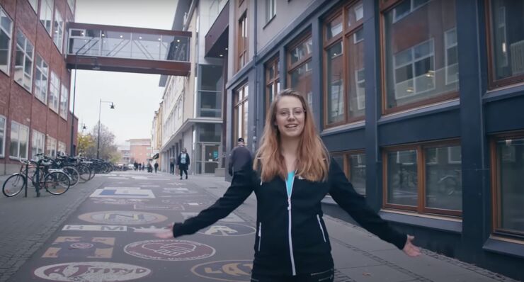 A young woman standing in front of a building looking welcoming