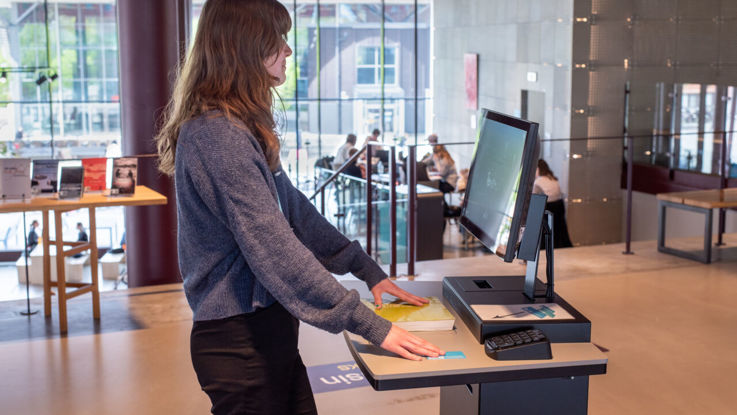 A female student borrowing a book at a self-check station.