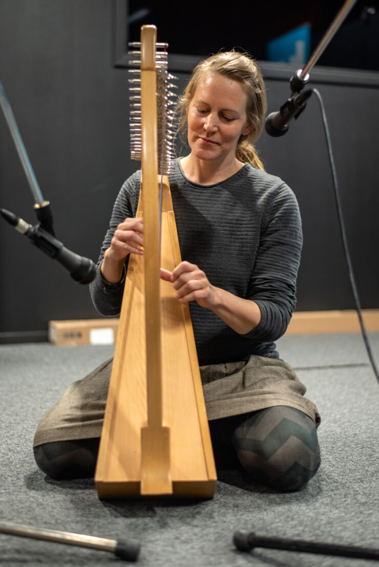 En person sitter på knä och spelar harpa. 