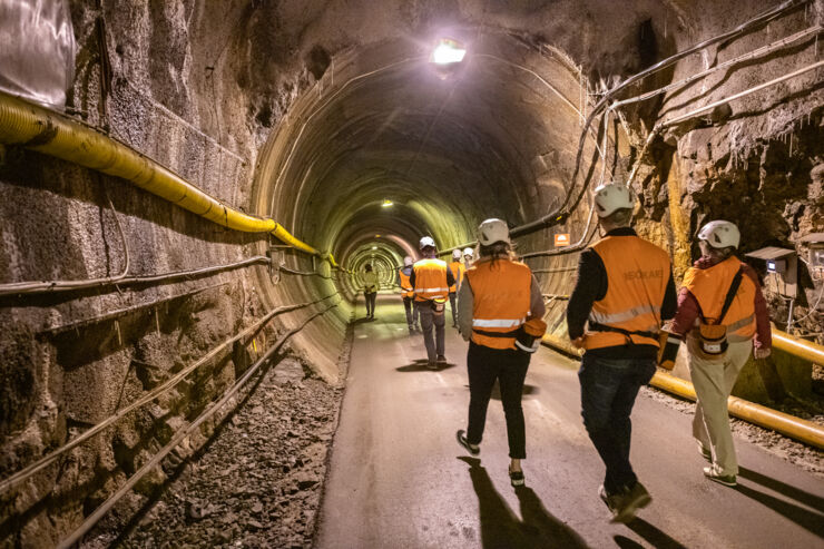 Personer i tunnel med hjälmar och orange västar.