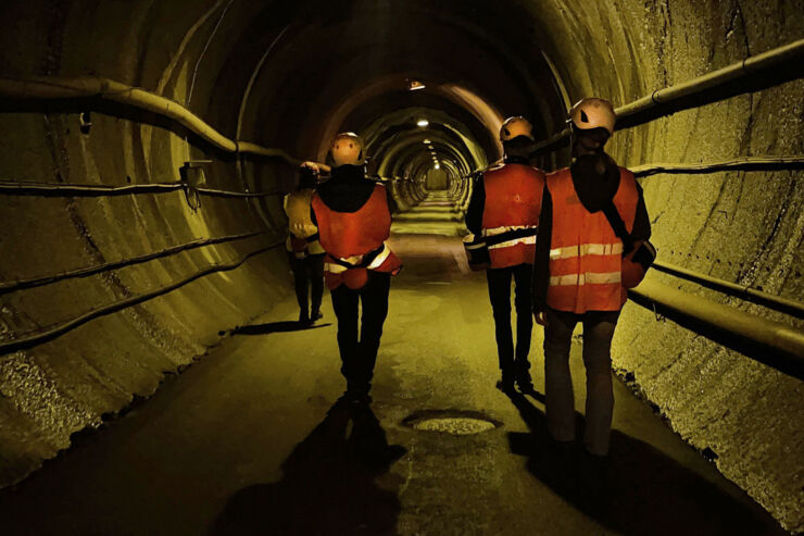 Tre personer i tunnel med hjälmar och orange västar.