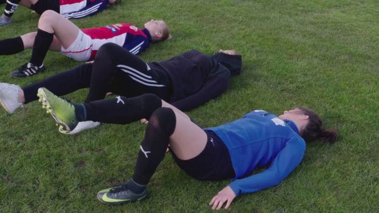 Flera tjejer ligger på marken och gör övningar för knäna.