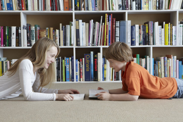 A girl and a boy reading books in the library