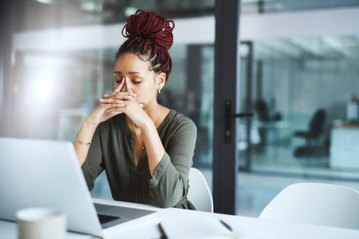 Woman that closes her eyes and has her hands on her face, she looks sad and tired.