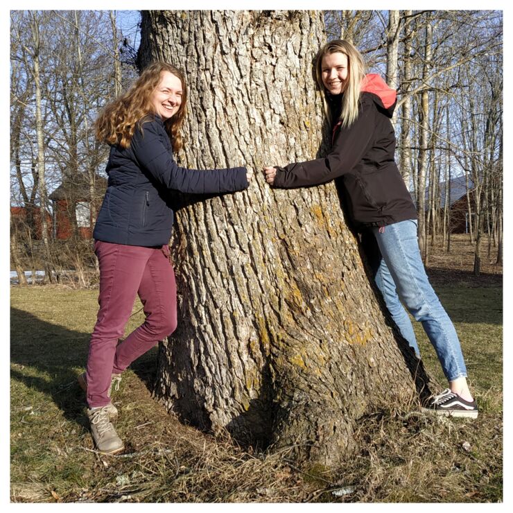The guests Matilda Arvidsson and Lisa Goldschmidtböing is hugging a tree and smiling into the camera.