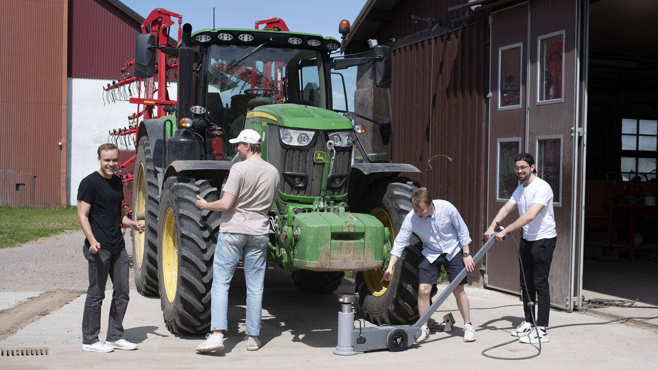 Fyra personer runt en grön traktor