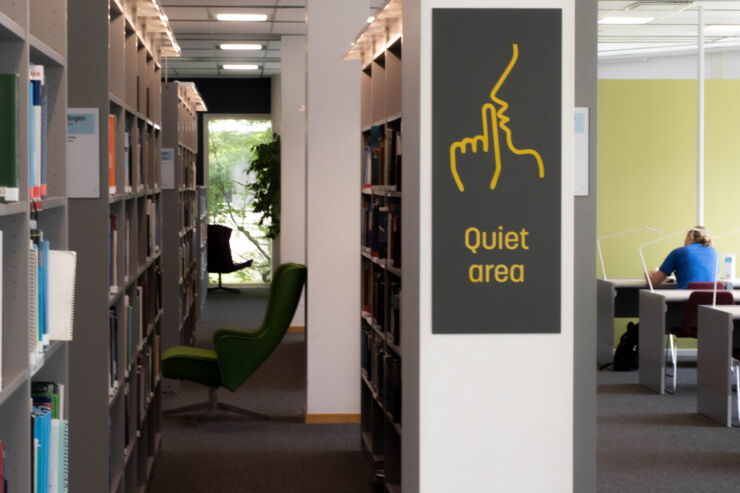 A person studying at a library and a sign with the text 