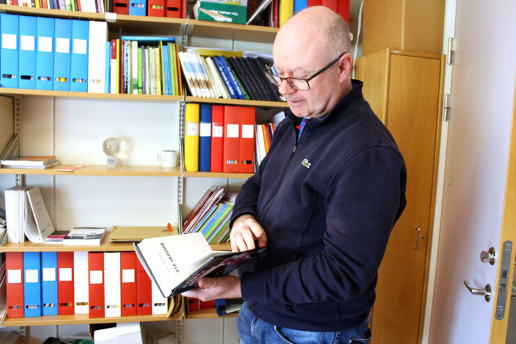 Robert Thornberg står och håller i en bok i arbetsrummet.
