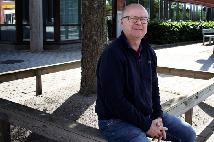 Robert Thornberg sitter på ett staket utomhus på universitetsområdet.