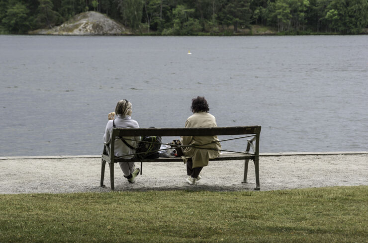 Två kvinnor sitter på en bänk och tittar ut över vattnet.