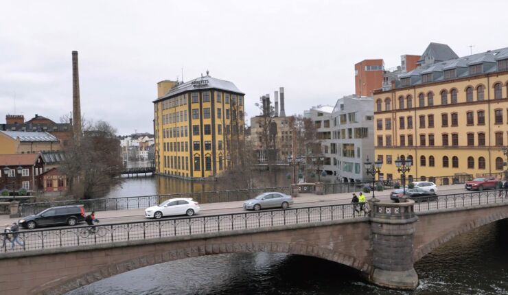 A city scape with a bridge across a river and industrial buildings in the background.