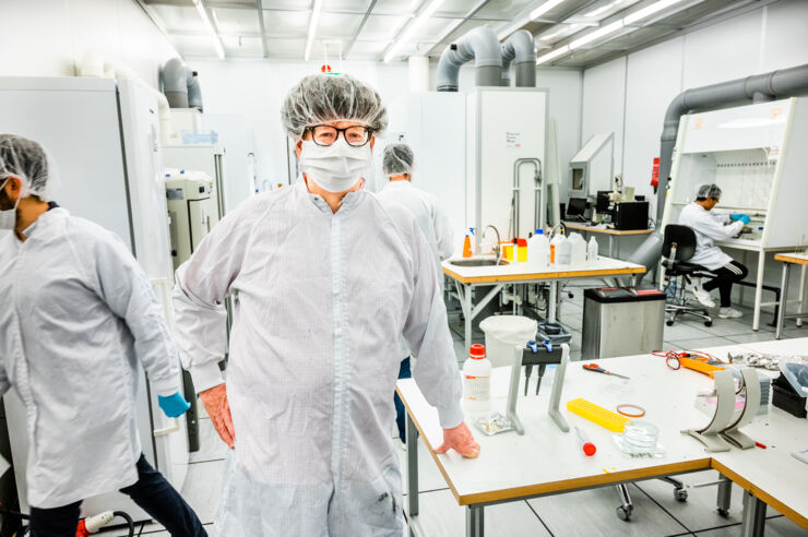 En person står med mask i ett laboratorium. 