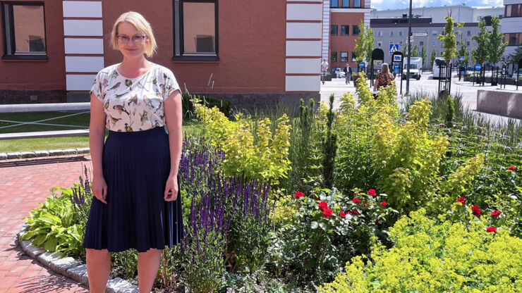 Kvinna står framför grönskande blommor i Campus US-området.