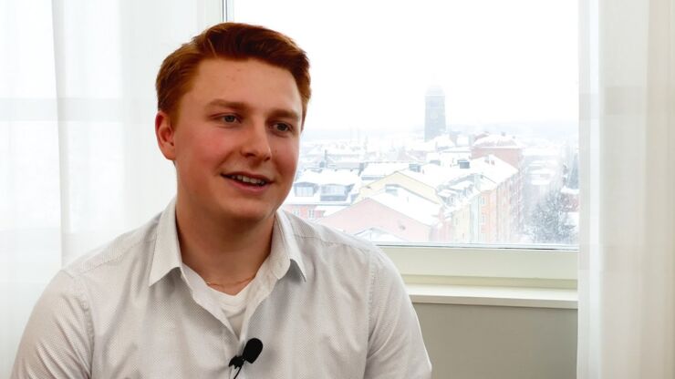 Manlig student intill fönster med utsikt över hustak