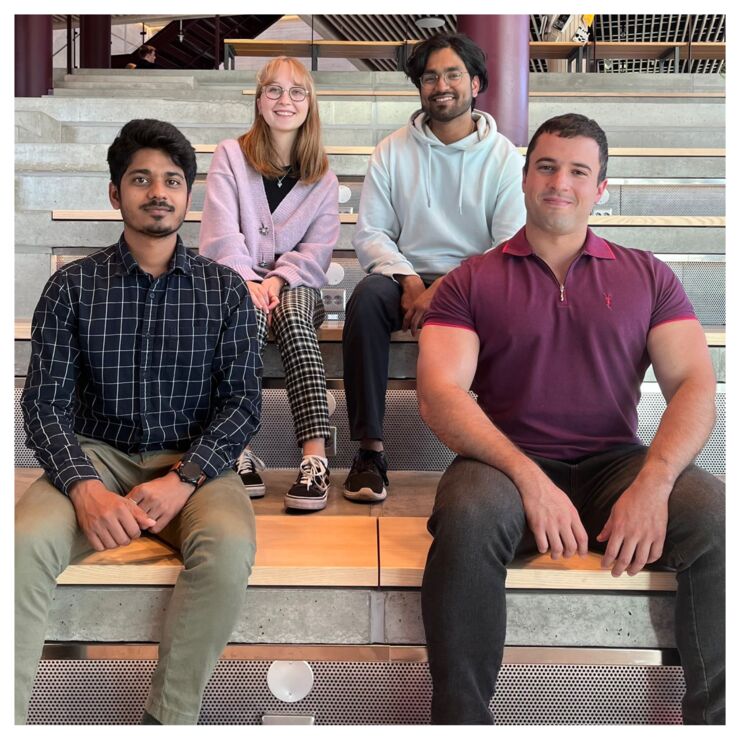 Four people smiling at the camera sitting in Studenthuset at Campus Valla.