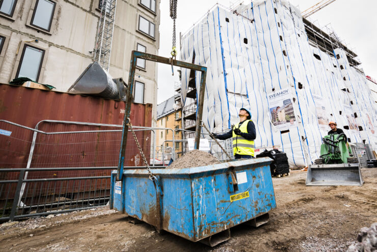 Byggplats, man i gul väst och hjälm tittar uppåt