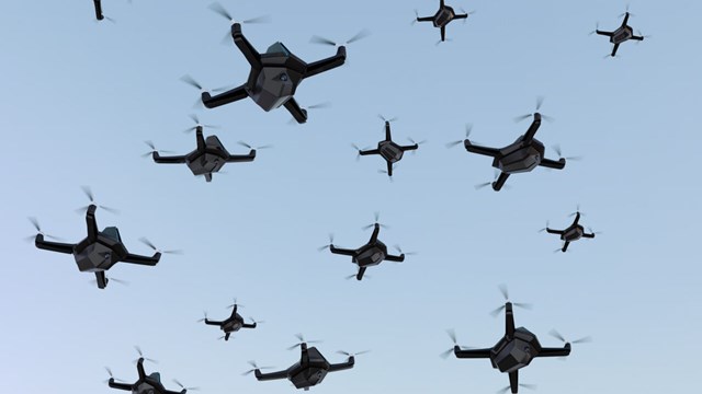 Swarm of drones on blue sky.