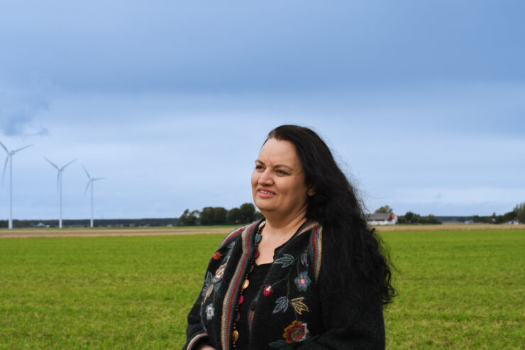 A portrait of a women. In the background you can see wind turbines