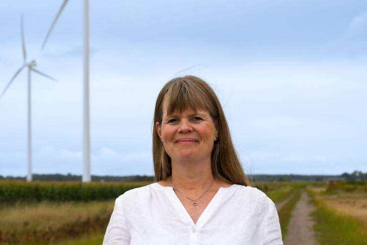 A portrait of a women. In the background you can see wind turbines