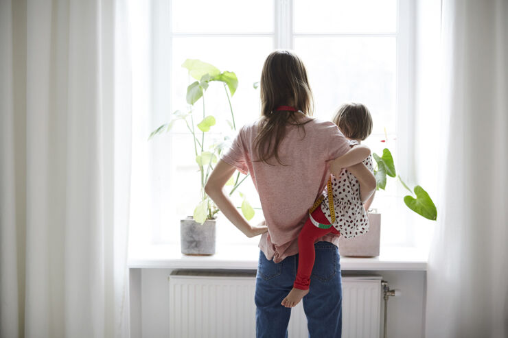 Mamma och barn står vända mot fönster