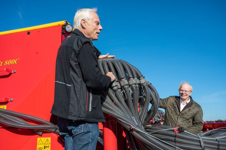Two persons standing on modern agricultural equipment.