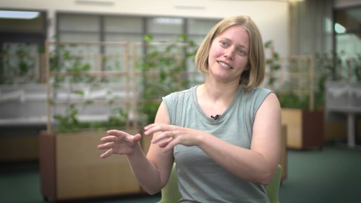 Young woman in olive-green shirt with green plants in the background