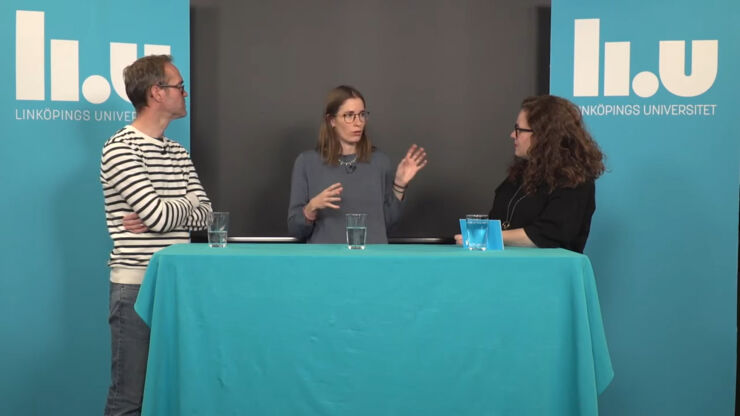 Man and woman listening to gesticulating woman at table with blue tablecloth