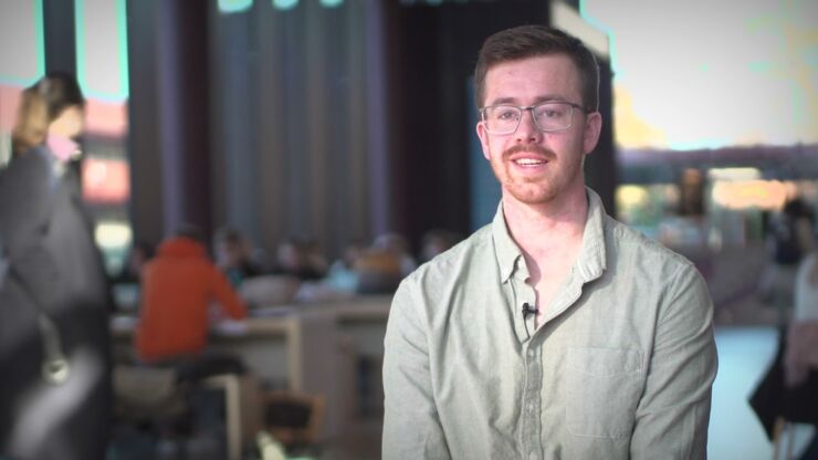 Young man in glasses and light shirt with blurry people in the background