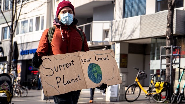 En man med skylt i handen som säger " Support your local Planet"