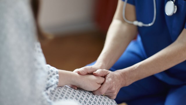 Sjukvårdspersonal som håller patient i händerna