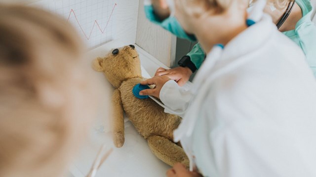 Barn leker doktor med nalle