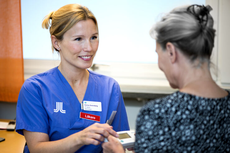 physician helps woman measure heart activity with an handheld EKG apparatus.