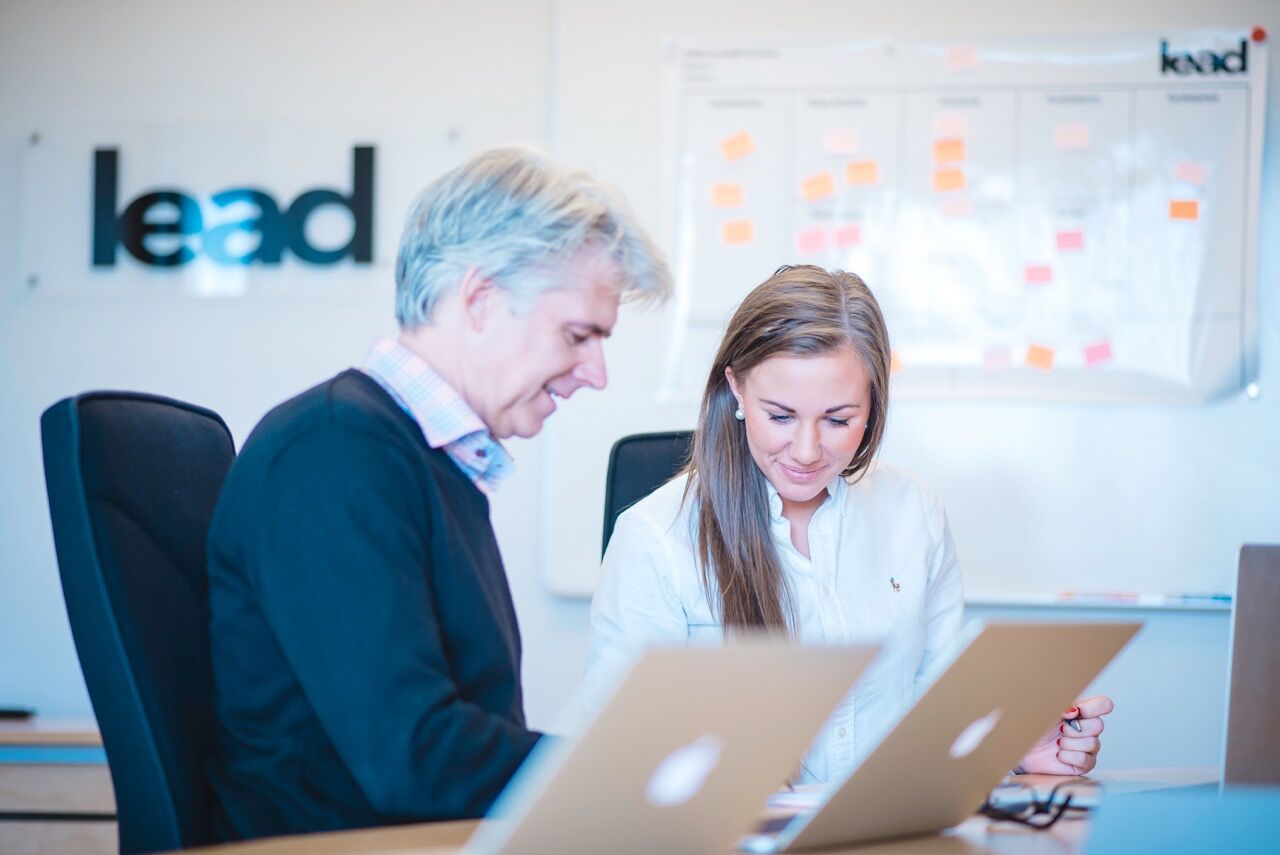 Two persons sitting at an office, talking.
