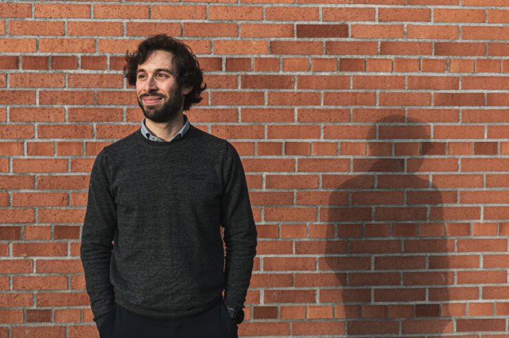 A man standing infront of a brick wall.