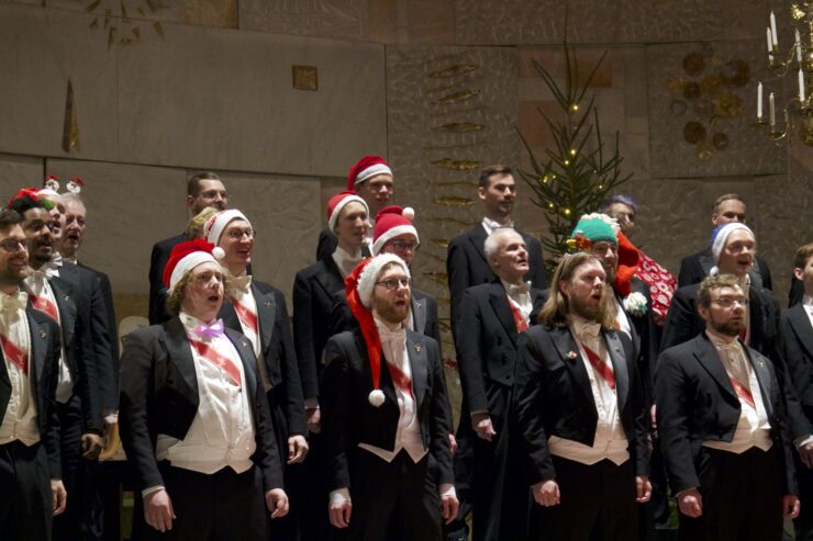 Men in evening dress and Santa hats singing