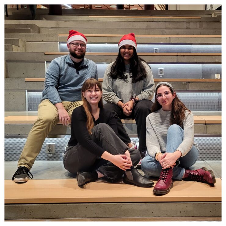 Four people sitting and two wearing santa hat.